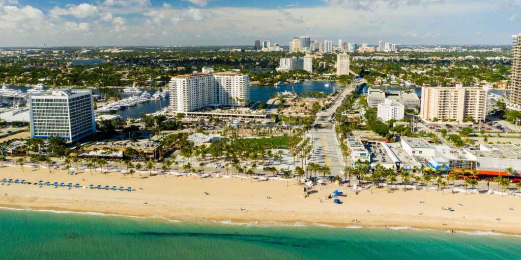 Aerial view of a coastal city with high-rise hotels along a sandy beach and turquoise ocean.